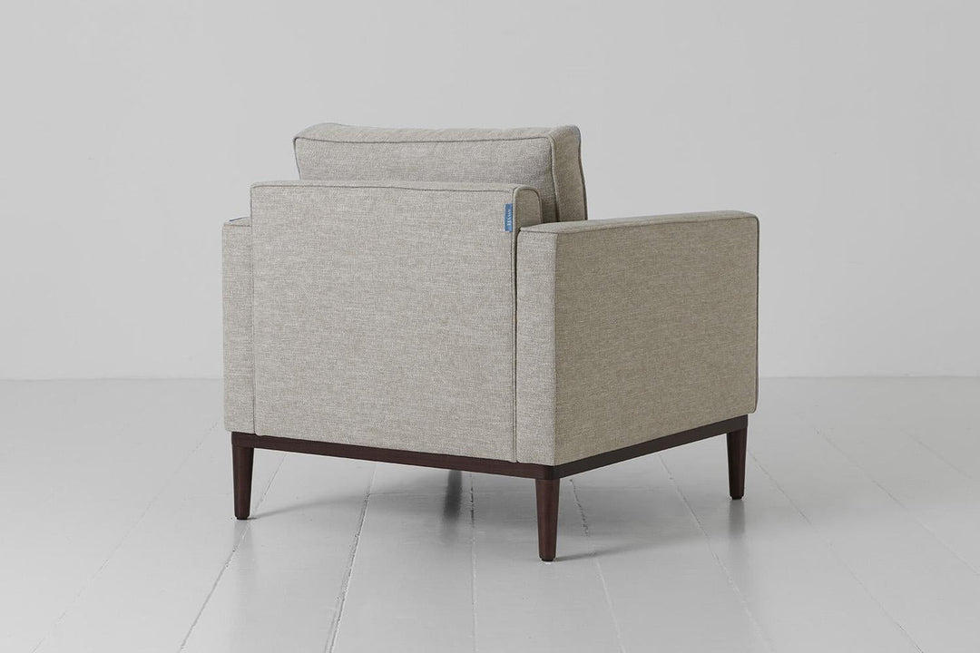 Gray armchair with wooden legs on a white floor and background