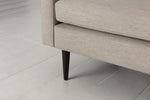 Load image into Gallery viewer, Close-up of a beige upholstered chair with dark wooden legs on a light gray floor.