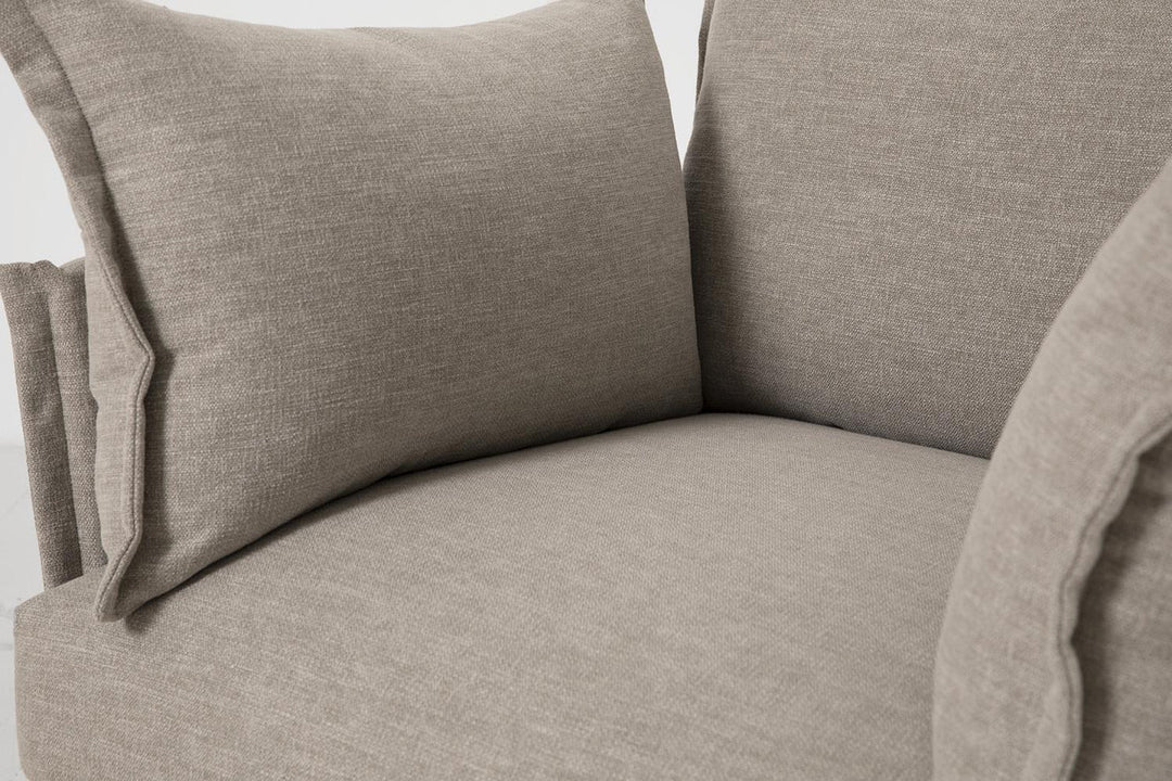 Close-up of a beige fabric armchair with a pillow.