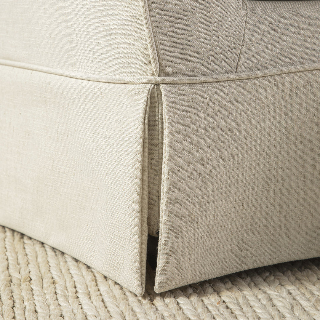 Close-up of a beige upholstered chair corner on a textured surface