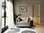 Load image into Gallery viewer, Living room with a gray armchair, decorative pillows, and a patterned rug.