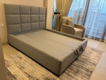 Load image into Gallery viewer, Gray upholstered bed in a room with a cityscape view
