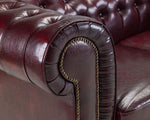 Load image into Gallery viewer, Close-up of a brown leather sofa with tufted backrest and decorative nailhead trim.