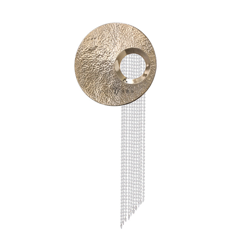 Decorative wall piece with round metallic top and hanging beads on a white background
