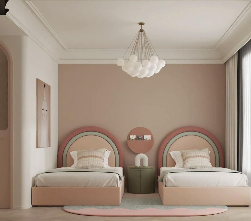 Modern bedroom with two pink beds, a round mirror, and a chandelier.