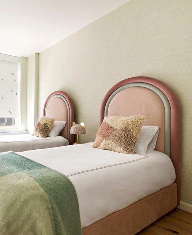 Bedroom with two pink beds against a light green wall.