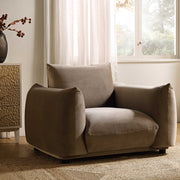 Beige armchair in a room with a window and decorative elements.