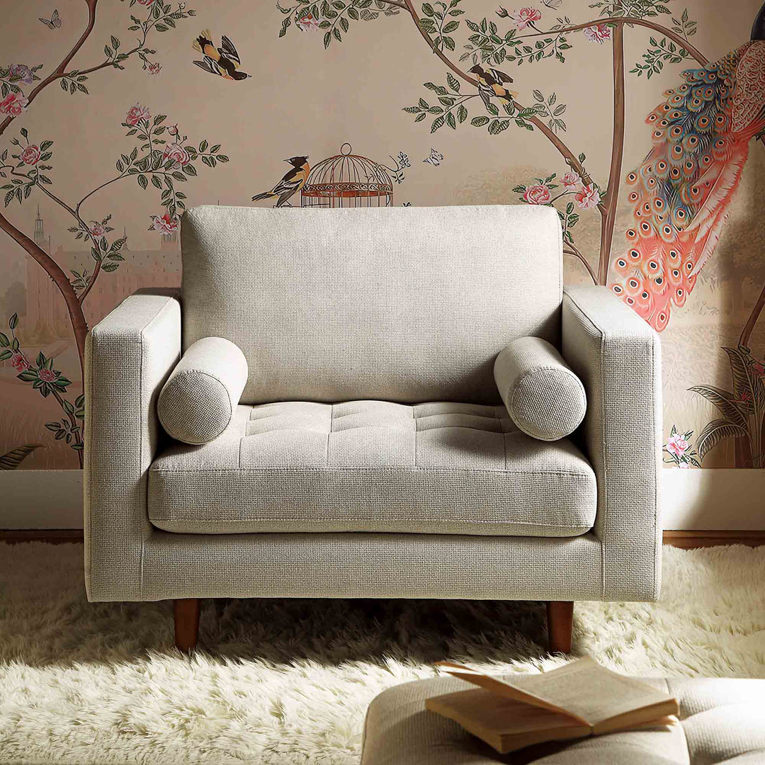 Gray armchair in a room with decorative wallpaper featuring birds and flowers.