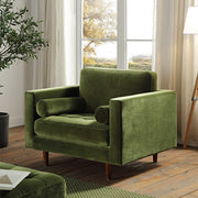 Green armchair in a room with large windows and a plant.