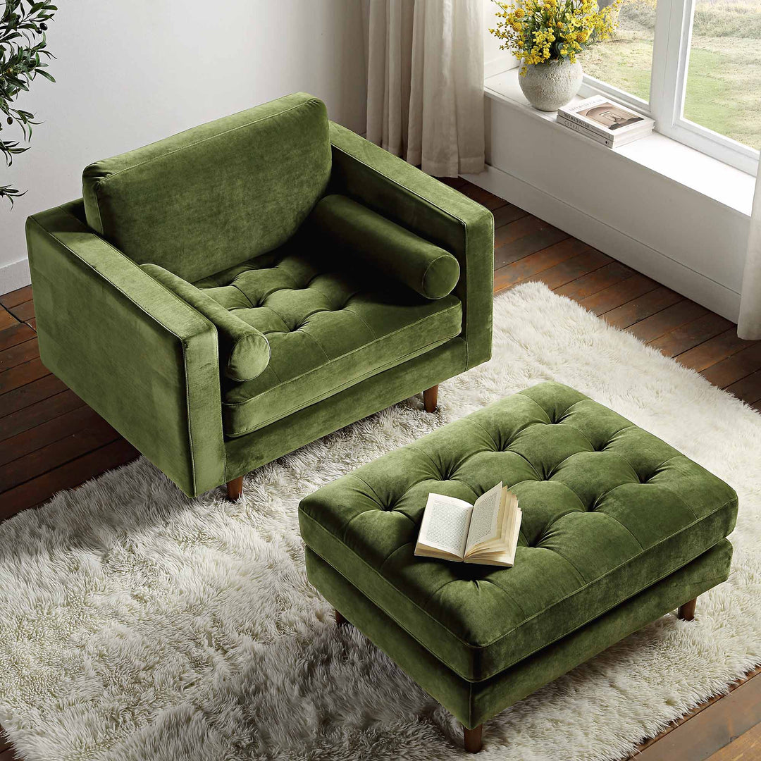 Green armchair and ottoman with a book on a white rug in a room with a window and plant.