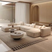 Modern living room with a beige sectional sofa, coffee table, and decorative elements.