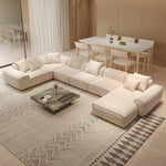 Load image into Gallery viewer, Modern living room with a beige sectional sofa, coffee table, and dining area.
