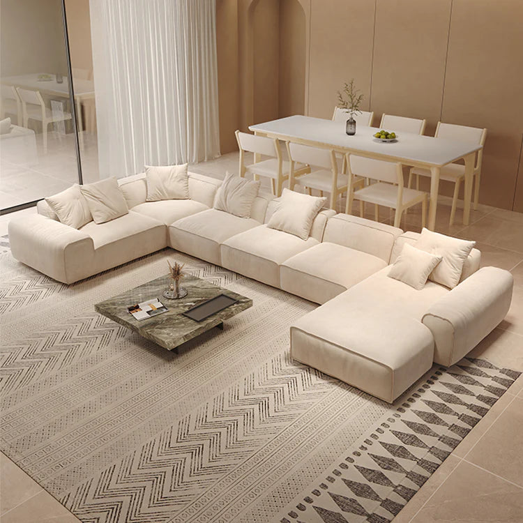 Modern living room with a beige sectional sofa, coffee table, and dining area.