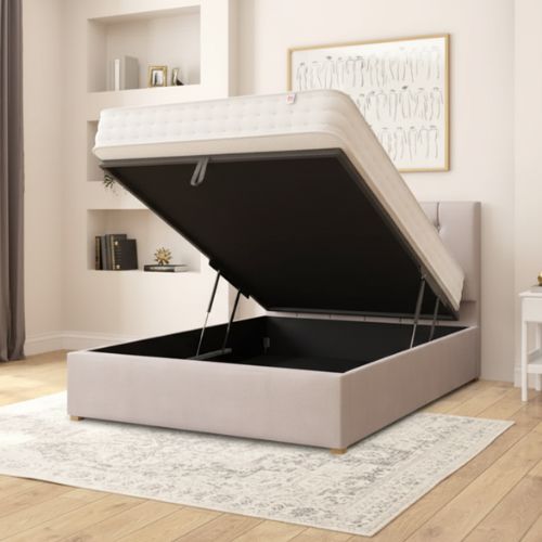 Beige bed with open storage compartment in a room with shelves and a rug.