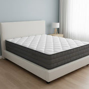 Gray and white mattress on a bed in a room with a lamp and curtains.