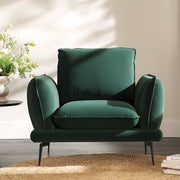 Green armchair in a room with a neutral wall and a small table with plants.