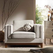Gray armchair in a living room setting with a plant and side table.