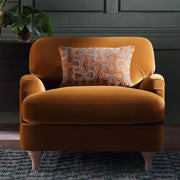 Orange armchair with a decorative pillow in a room setting