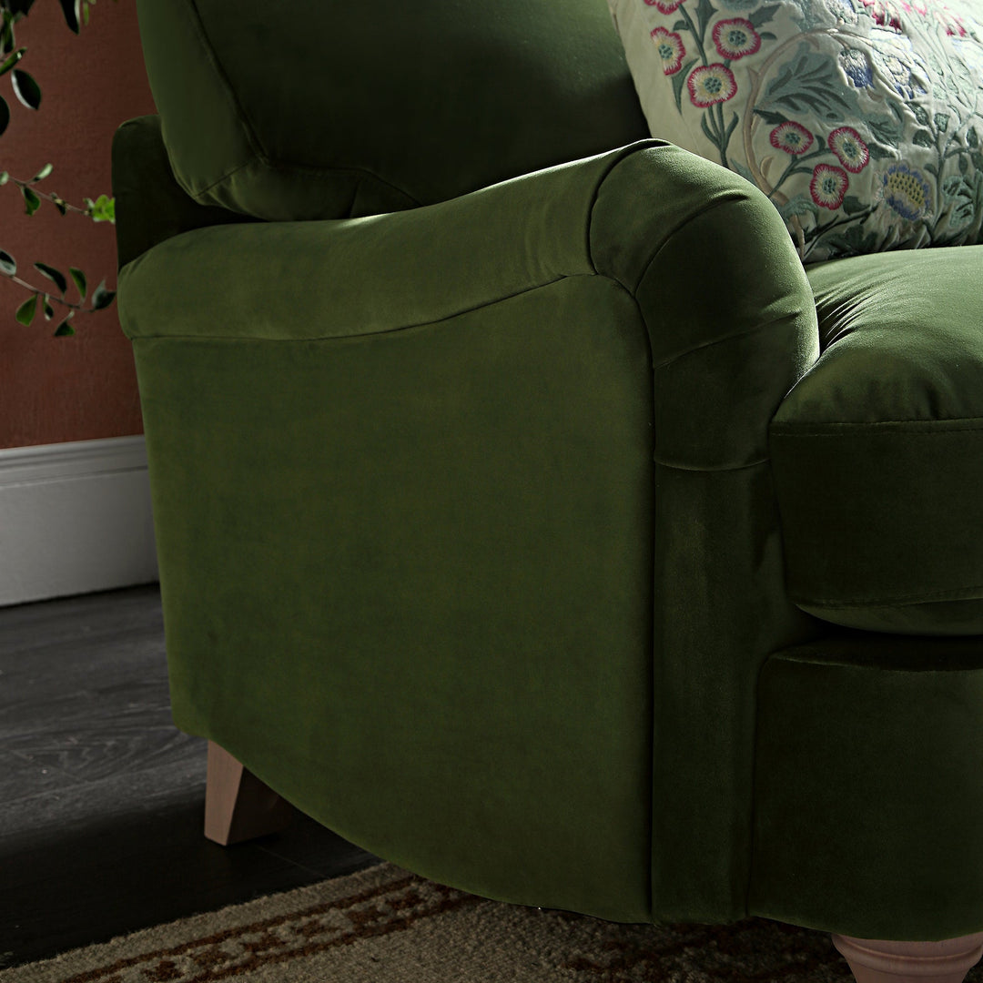 Green armchair with floral-patterned pillow in a room setting