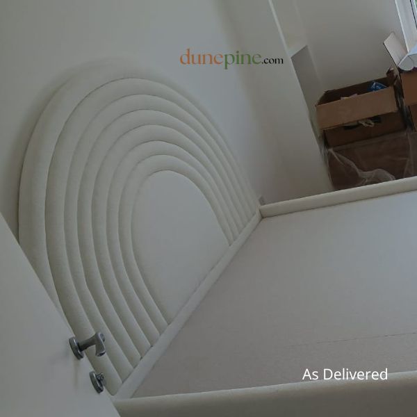 White upholstered headboard with circular design on a bed frame, brand 'dunepine' visible.