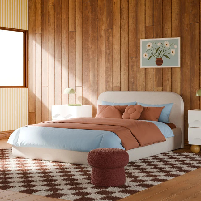 Modern bedroom with wooden walls, a bed with blue and brown bedding, and a decorative rug.