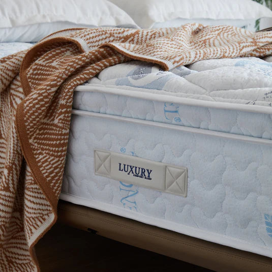 Mattress with a blanket draped over it, featuring a 'Luxury' label.
