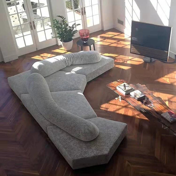 Gray sectional sofa in a living room with wooden floor and TV.