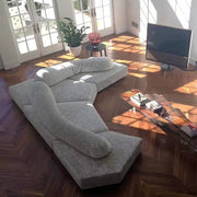 Gray sectional sofa in a living room with wooden floor and TV.