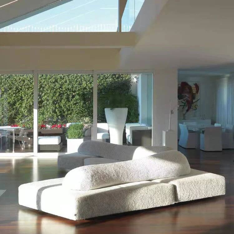 Modern white sofa in a stylish living room with large windows.