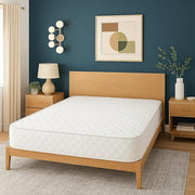 Bedroom with wooden bed frame and white mattress against a blue wall.