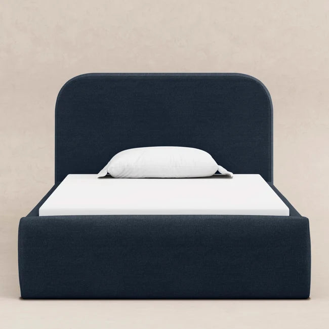 Navy bed frame with white mattress and pillow on a beige background