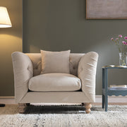 Beige armchair in a living room setting with a side table and lamp.