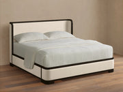 Bed with white bedding and black frame on a wooden floor.