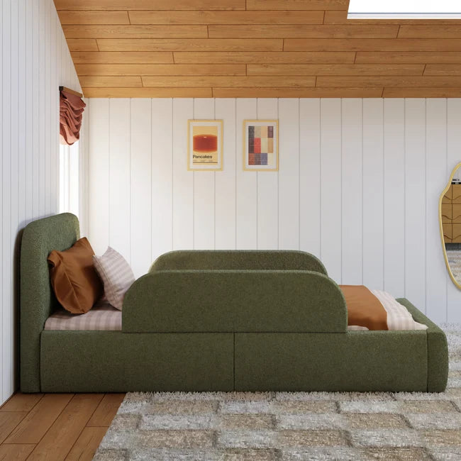 Green upholstered bed with pillows in a room with wooden ceiling and white walls.