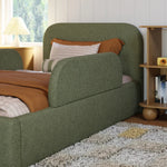 Load image into Gallery viewer, Green upholstered bed with brown and white pillows in a room with a window and bookshelf.