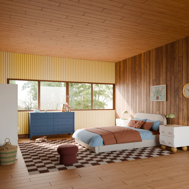 Modern bedroom with wooden walls, a bed, dresser, and large window.
