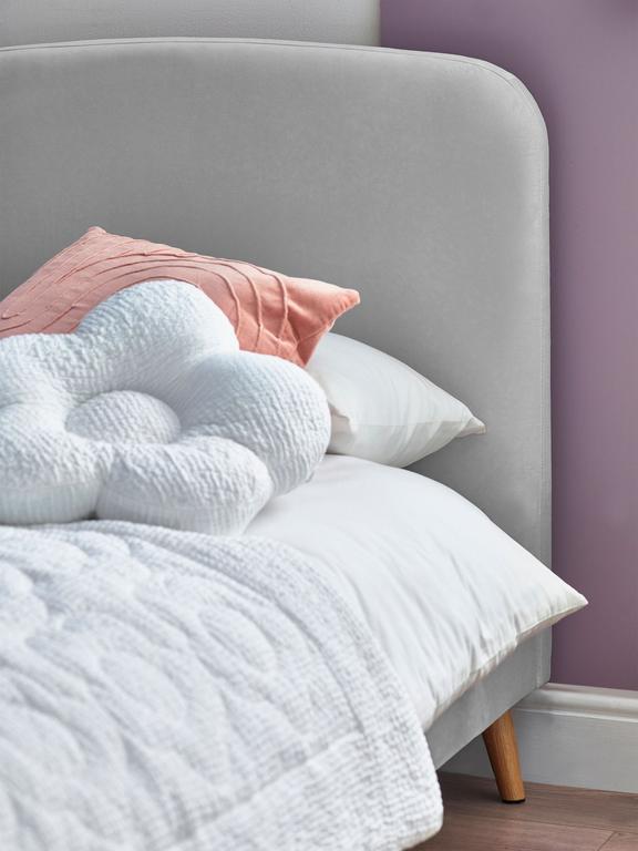 Gray upholstered headboard with white bedding and pink pillow against a purple wall.