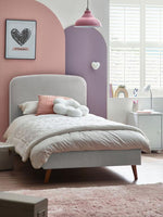 Load image into Gallery viewer, Children's bedroom with a gray bed, pink walls, and decorative elements.