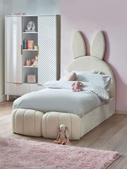 Children's bedroom with a bed featuring bunny ears and a cabinet with books and toys.