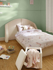 Children's bedroom with a bed and storage ottoman against a green wall.