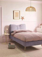 Neatly made bed with a purple headboard and pink bedding in a bedroom setting.